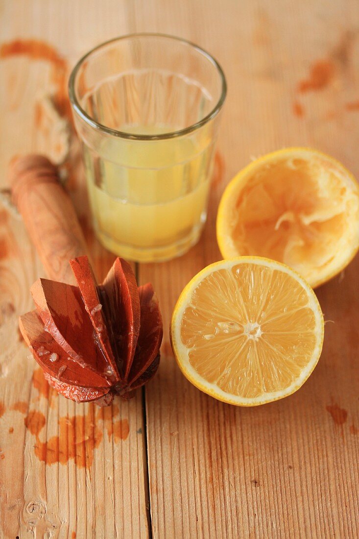 Lemon juice, a lemon squeezer and a halved lemon