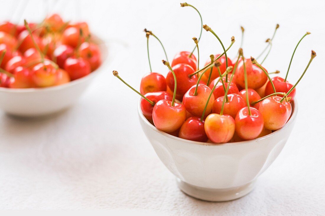 Two white bowl of fresh cherries