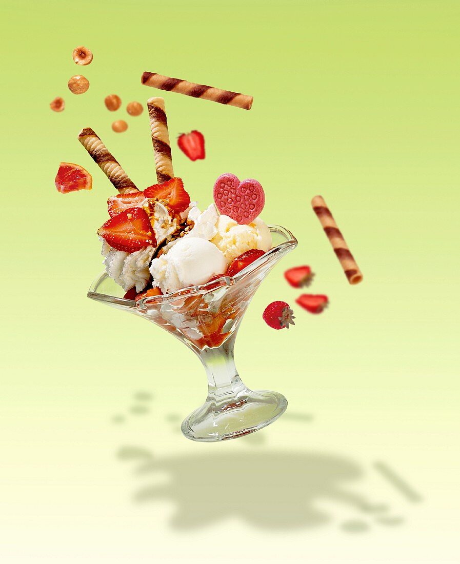 Action shot of an ice cream sundae with vanilla ice cream, lemon ice cream, cream and fresh strawberries