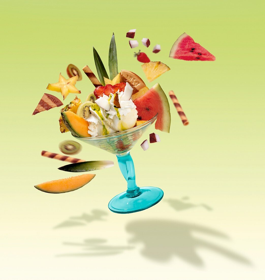 A fruit sundae with lemon ice cream, fresh fruit, cream and wafers, flying through the air