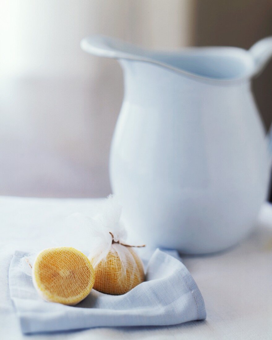 Halved Meyer Lemon Wrapped in Cheesecloth with a Water Pitcher