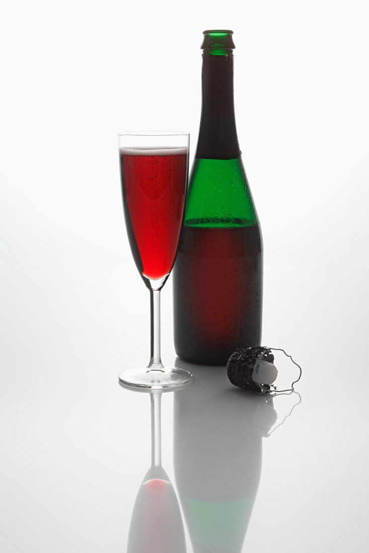 Roter Sekt (Flasche, Sektglas und Sektkorken)