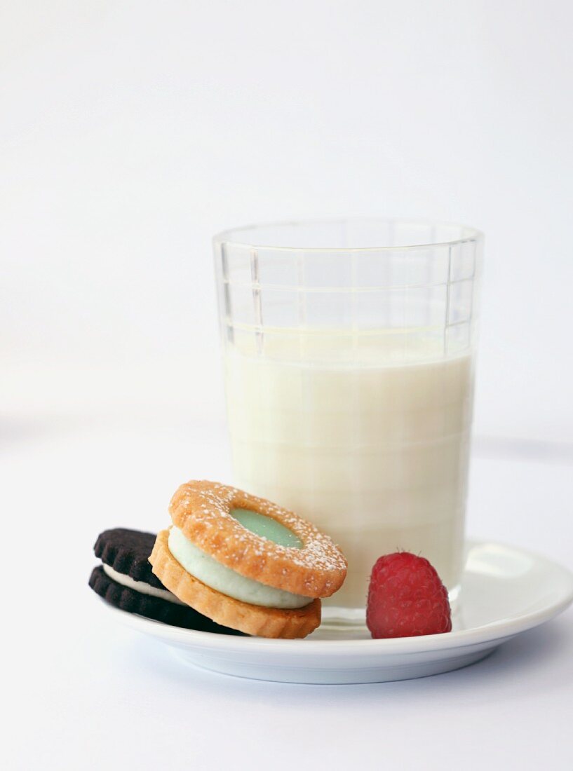 Two Cookies with a Raspberry and a Glass of Milk; On a Plate
