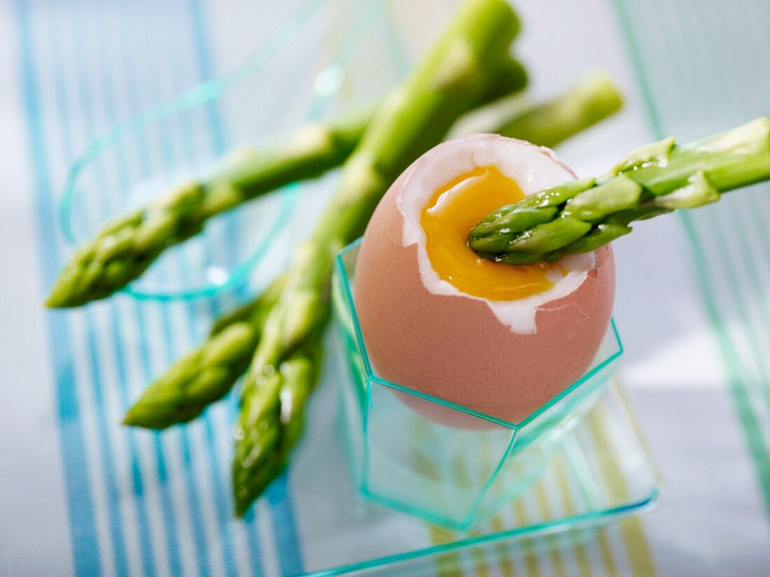 A soft boiled egg with green asparagus