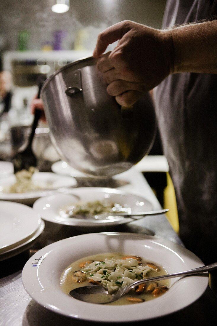 Muschelsuppe auf Bandnudeln gießen