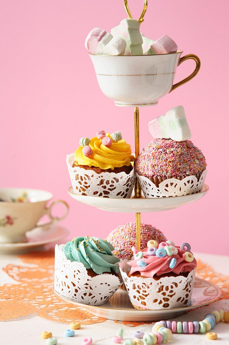 An assortment of cupcakes and marshmallows on a tiered cake stand
