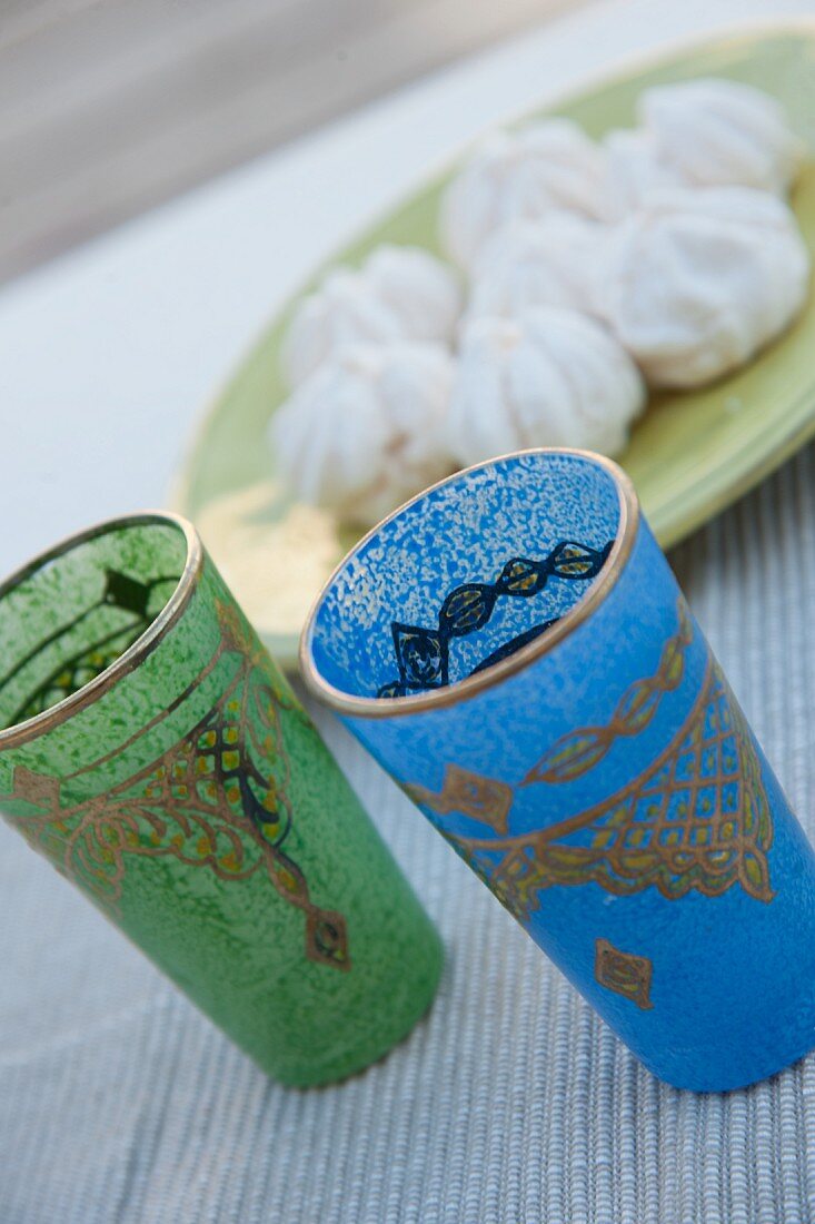 Coloured tea glasses with Oriental patterns next to dish of confectionery