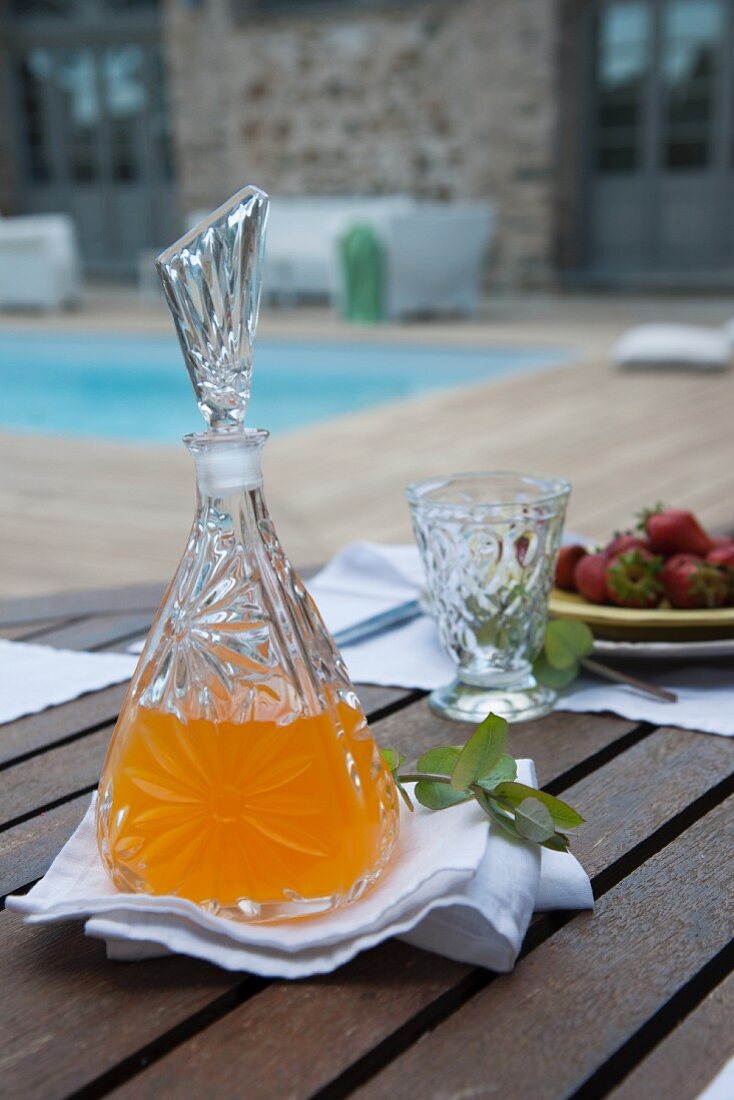 Set terrace table - refreshing drink in crystal carafe and glass on white linen napkin