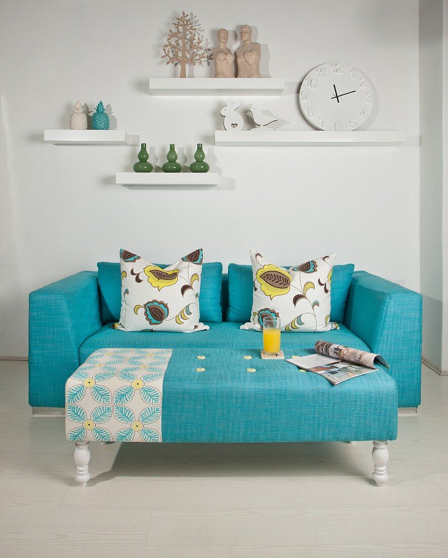 Ornaments on white shelving above turquoise couch and ottoman