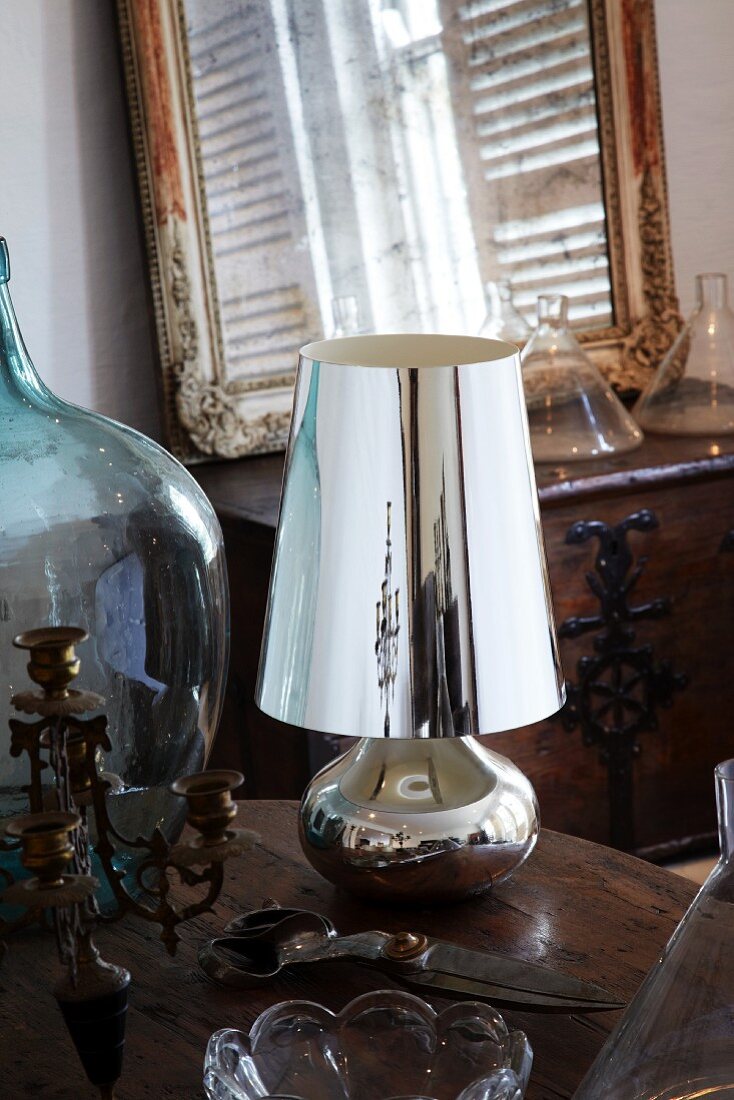 Vintage candlestick, garden shears, silver table lamp and demijohn on wooden table