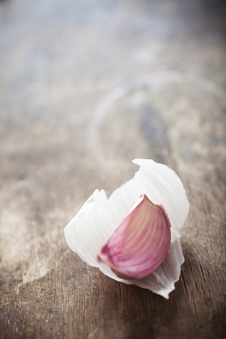 A clove of garlic on a wooden surface