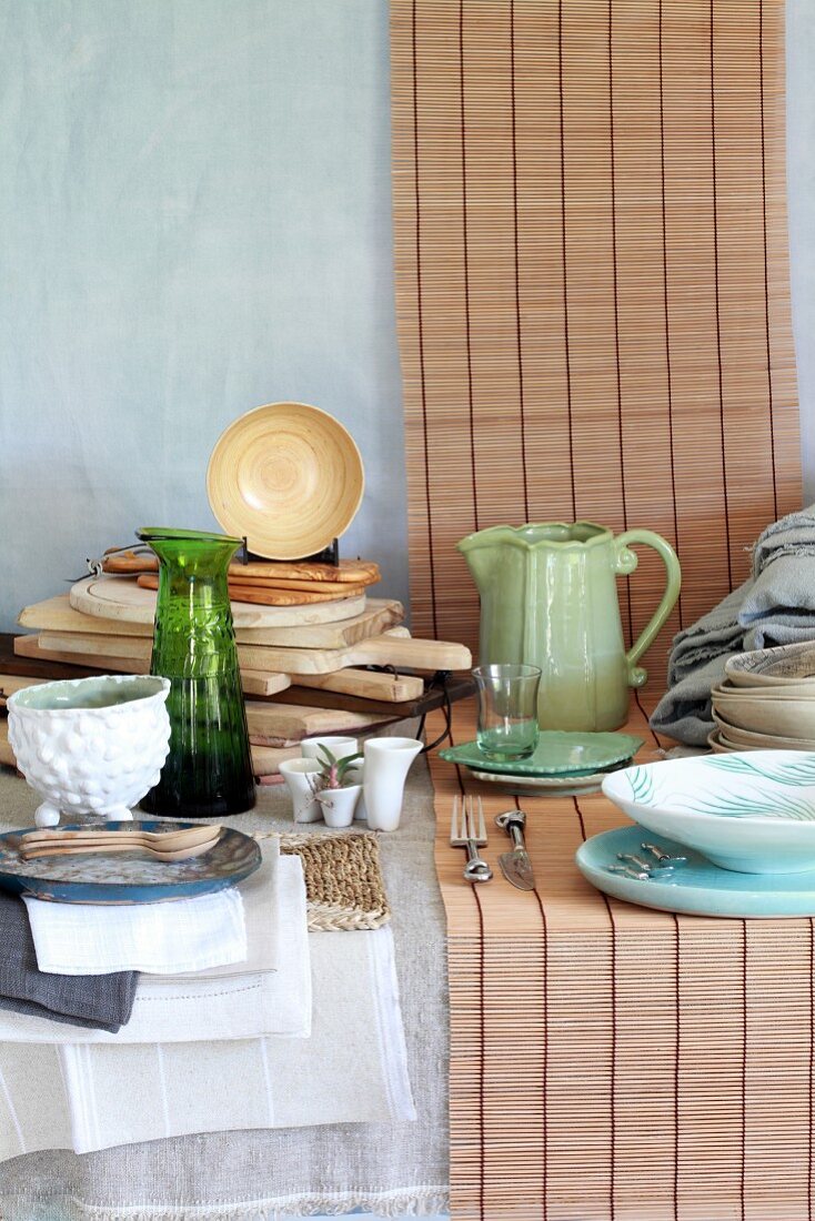 Crockery, wooden chopping boards and table linen in natural colours on a table