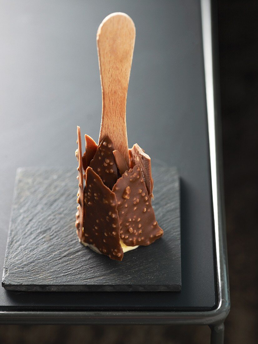 An ice lolly coated with chocolate and chopped nuts