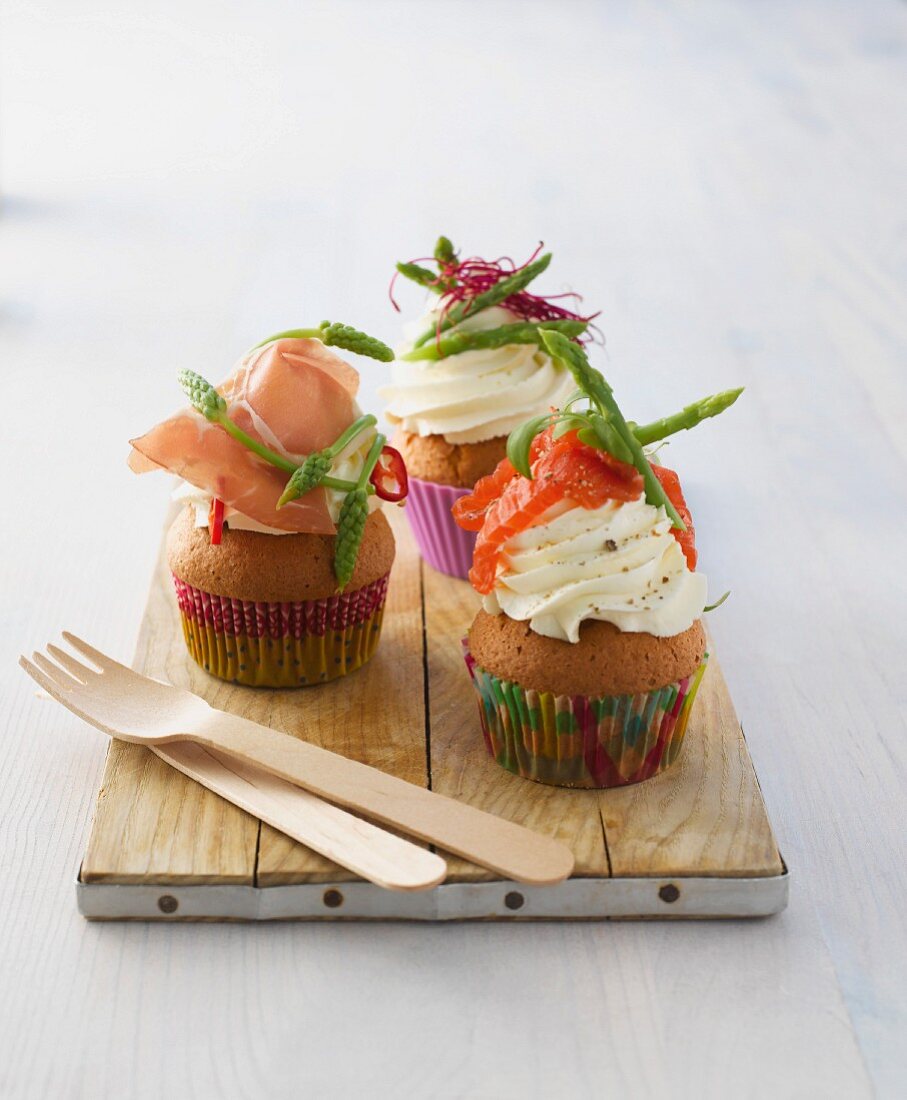 Three assorted savoury cupcakes on a wooden board