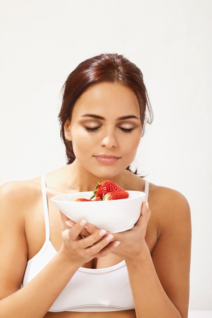 A woman holding a bowl of strawberries