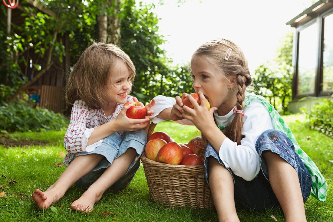 Two girls eating apples in the garden