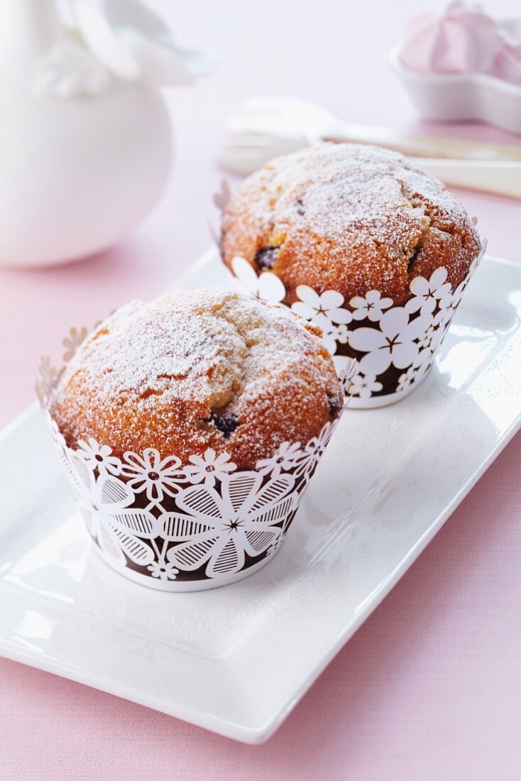 Muffins mit Puderzucker in Förmchen mit Blumenmotiv