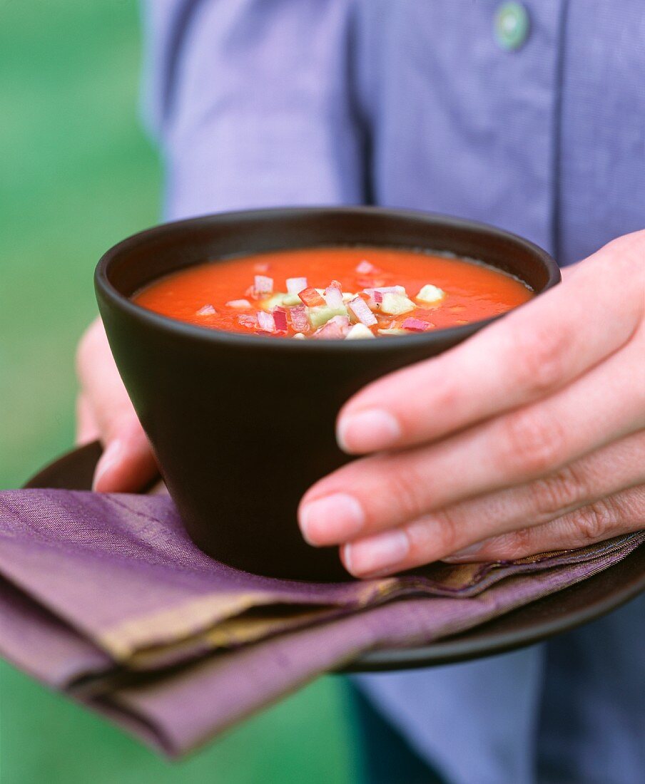 Hand hält würzige Tomatensuppe