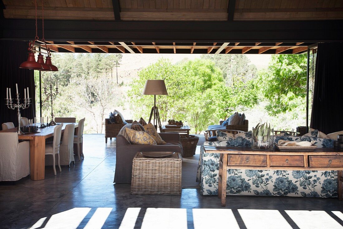 Living room terrace with floral sofa, rattan side table and dining table in background