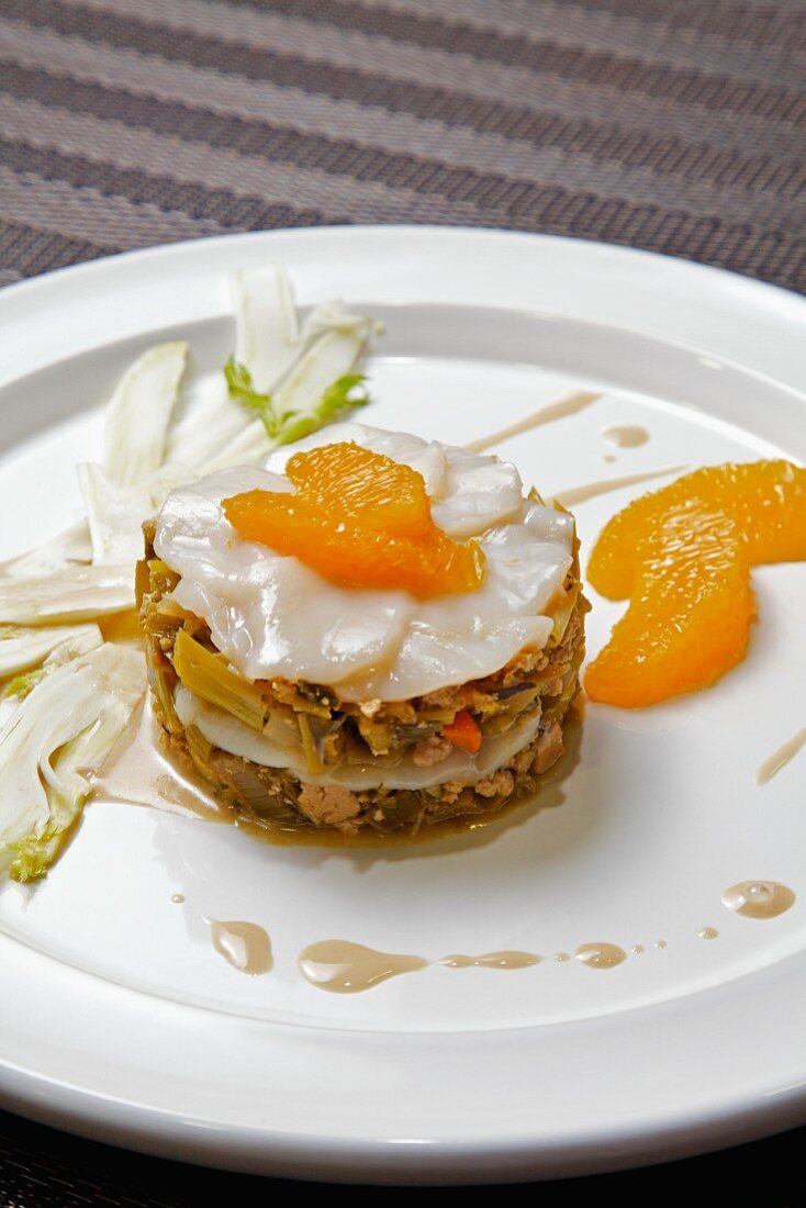 A small, circular stack of scallops, tofu and leek