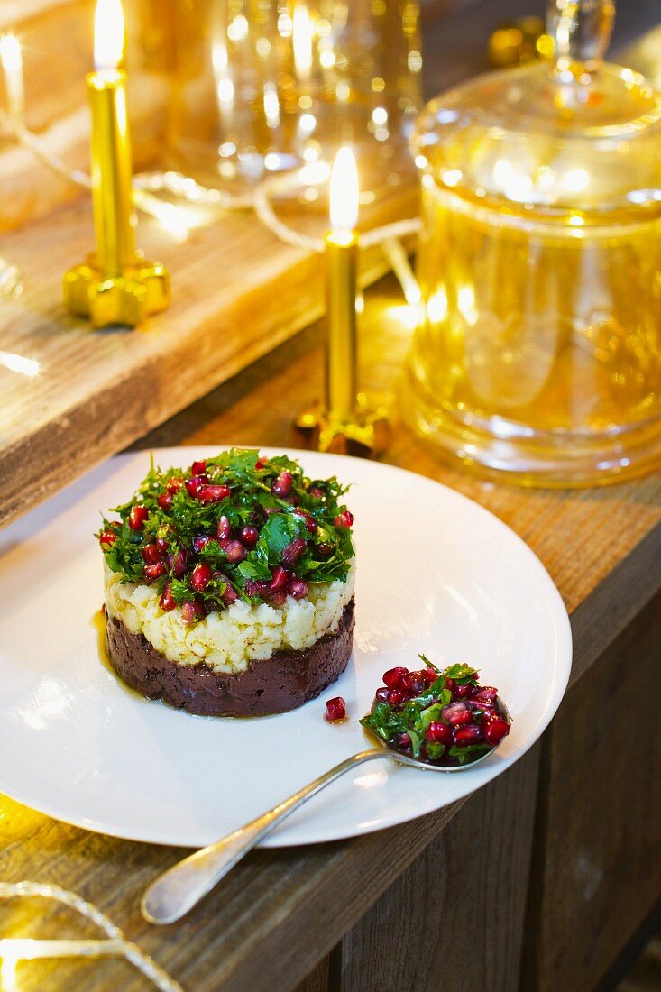 Individual prune layer cake topped with parsley and pomegranate salad