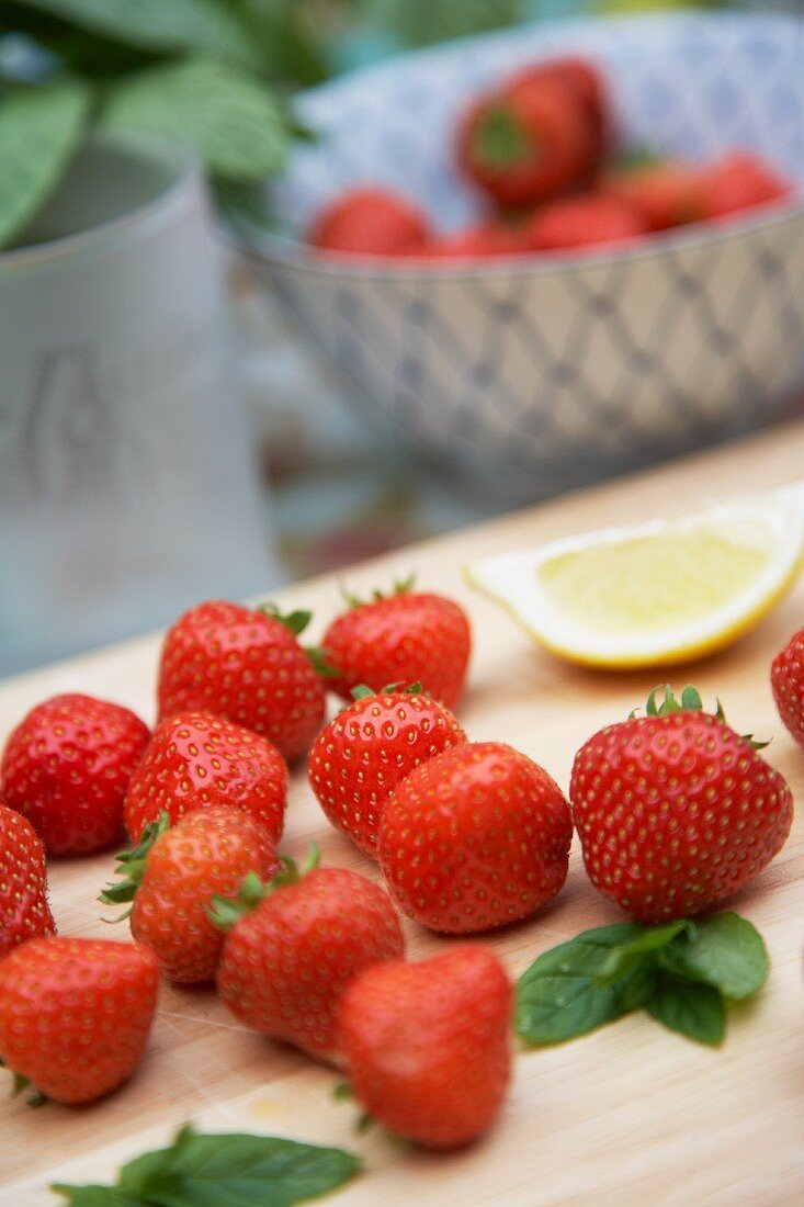 Fresh strawberries, mint leaves and a wedge of lemon