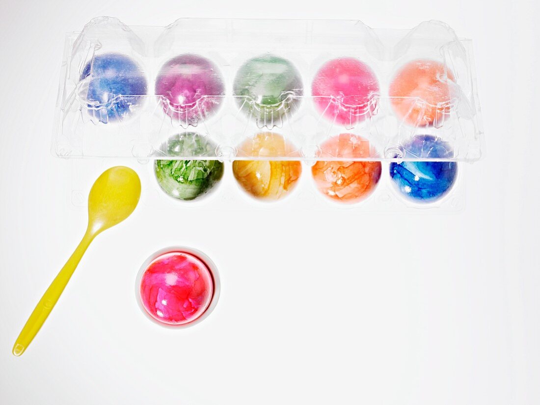 Bunt gefärbte Eier in Eierbecher & durchsichtigem Eierkarton