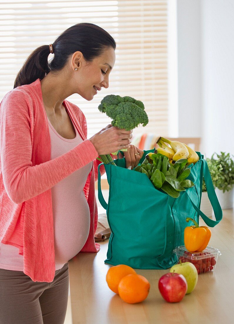 Schwangere Frau packt Lebensmittel aus