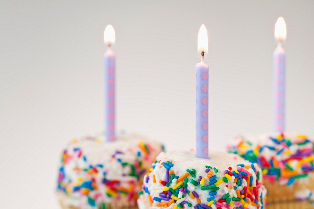 Lit candles on decorated cakes