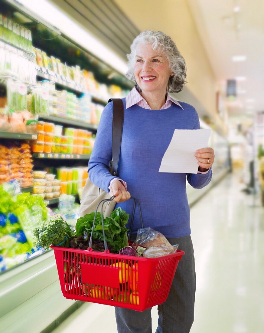 Ältere Frau trägt Warenkorb im Supermarkt