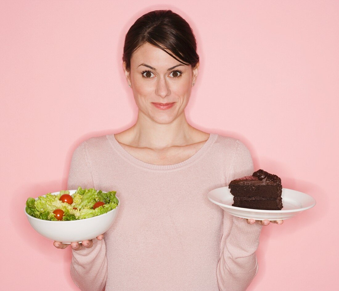 Frau hält Salat und Kuchen