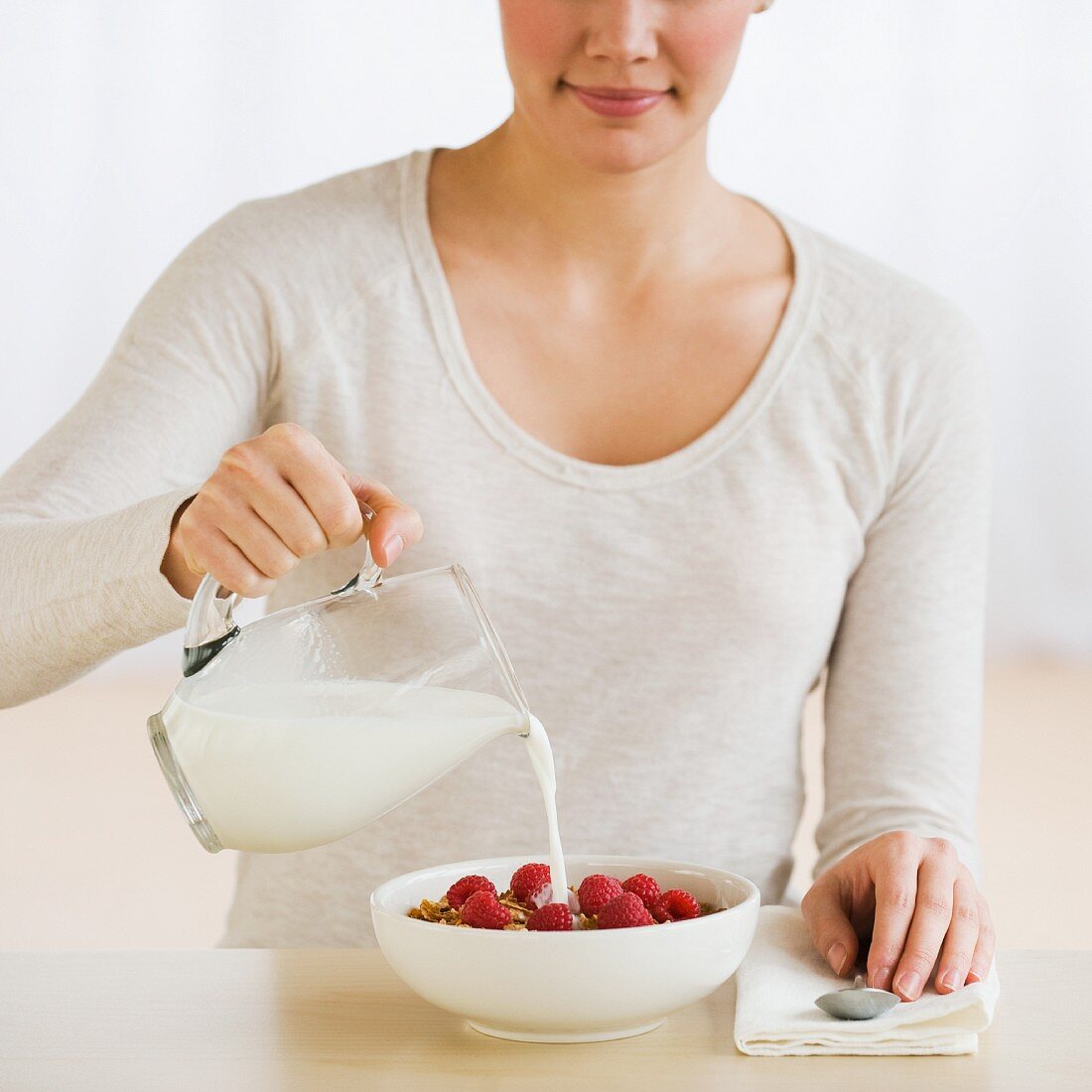Woman pouring milk on cereal