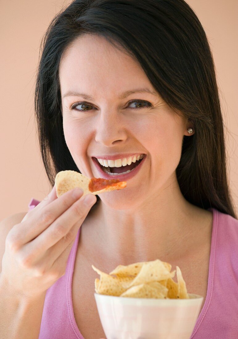Frau isst Chips mit Dip