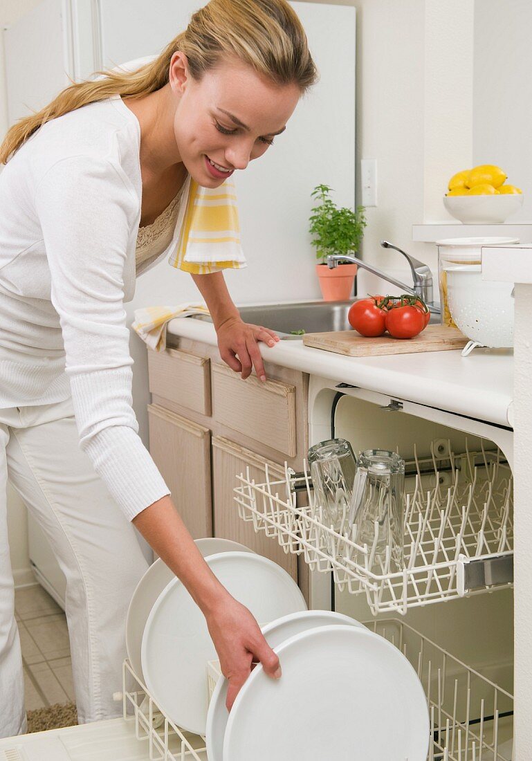 Woman loading plates in dishwasher