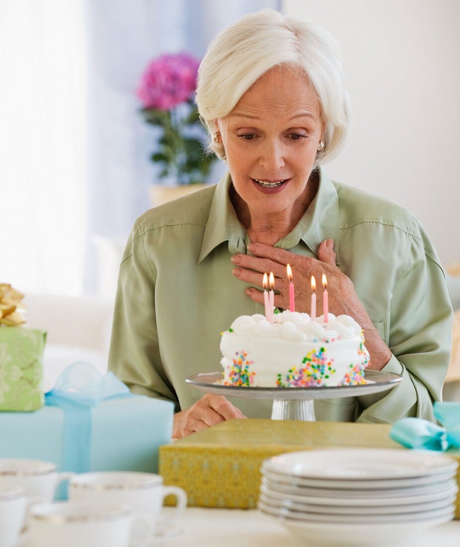 Ältere Frau schaut auf Geburtstagstorte