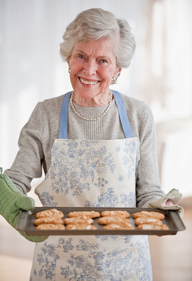 Ältere Frau hält Tablett mit selbst gebackenen Plätzchen