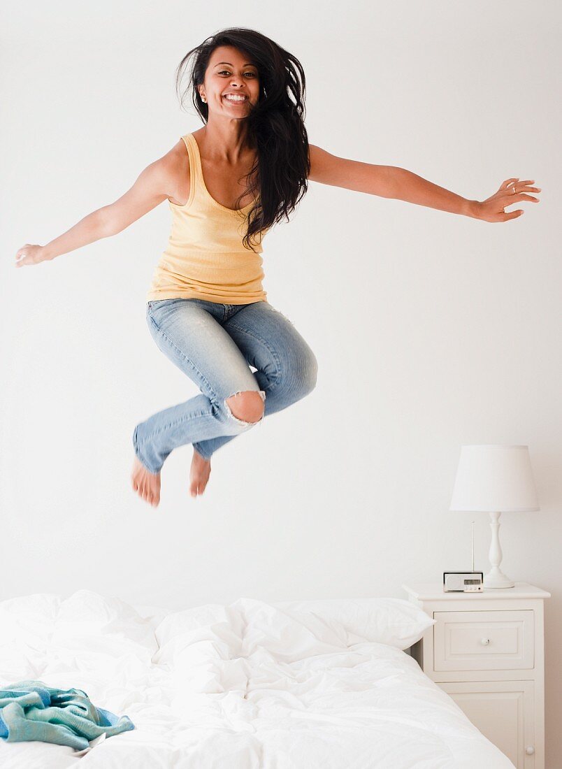 Frau springt auf dem Bett