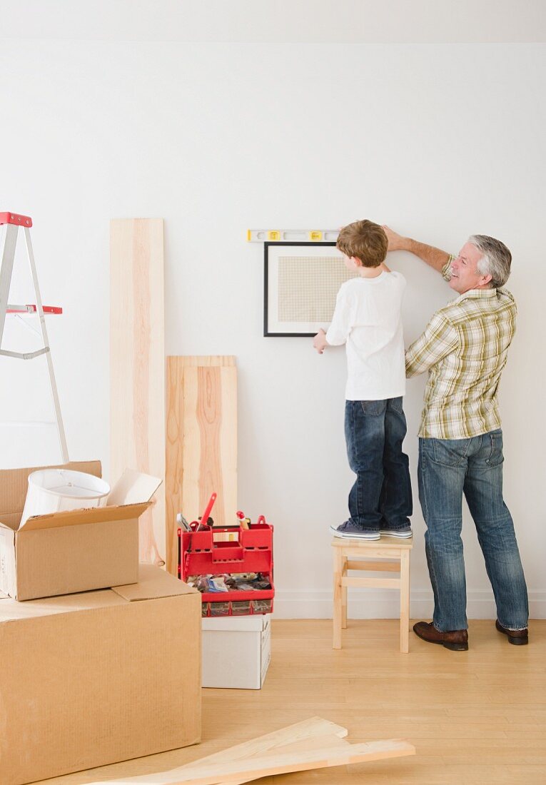 Vater und Sohn hängen Bilder an die Wand