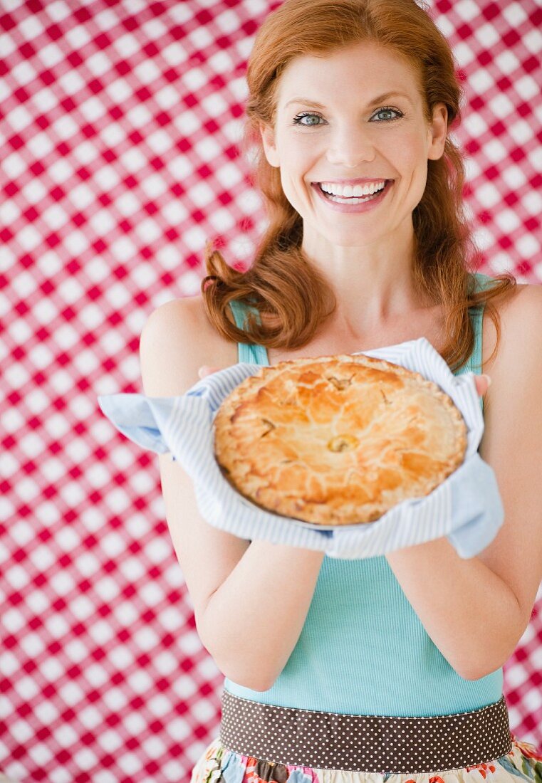 Frau hält einen frisch gebackenem Apfelkuchen