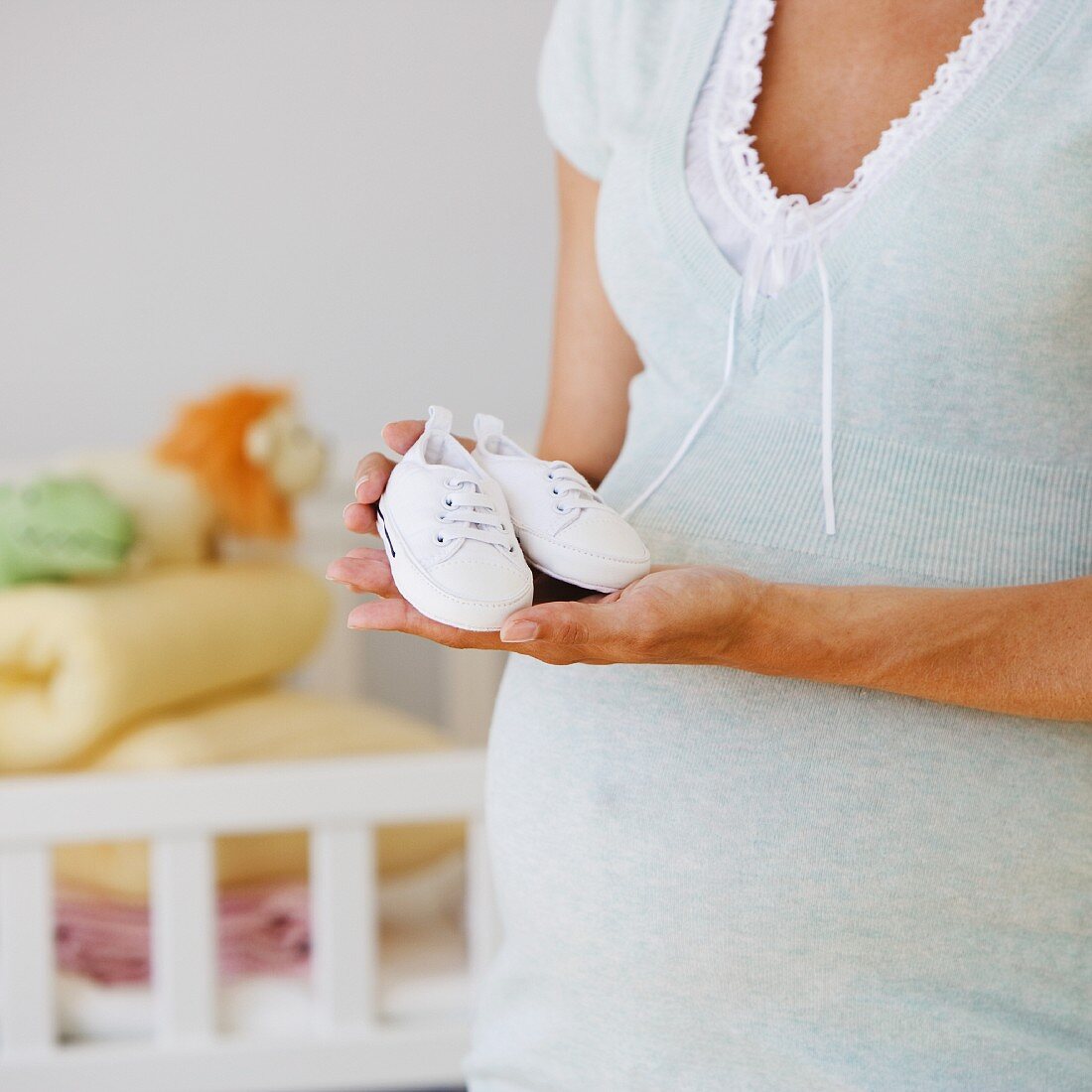 Pregnant woman holding baby shoes