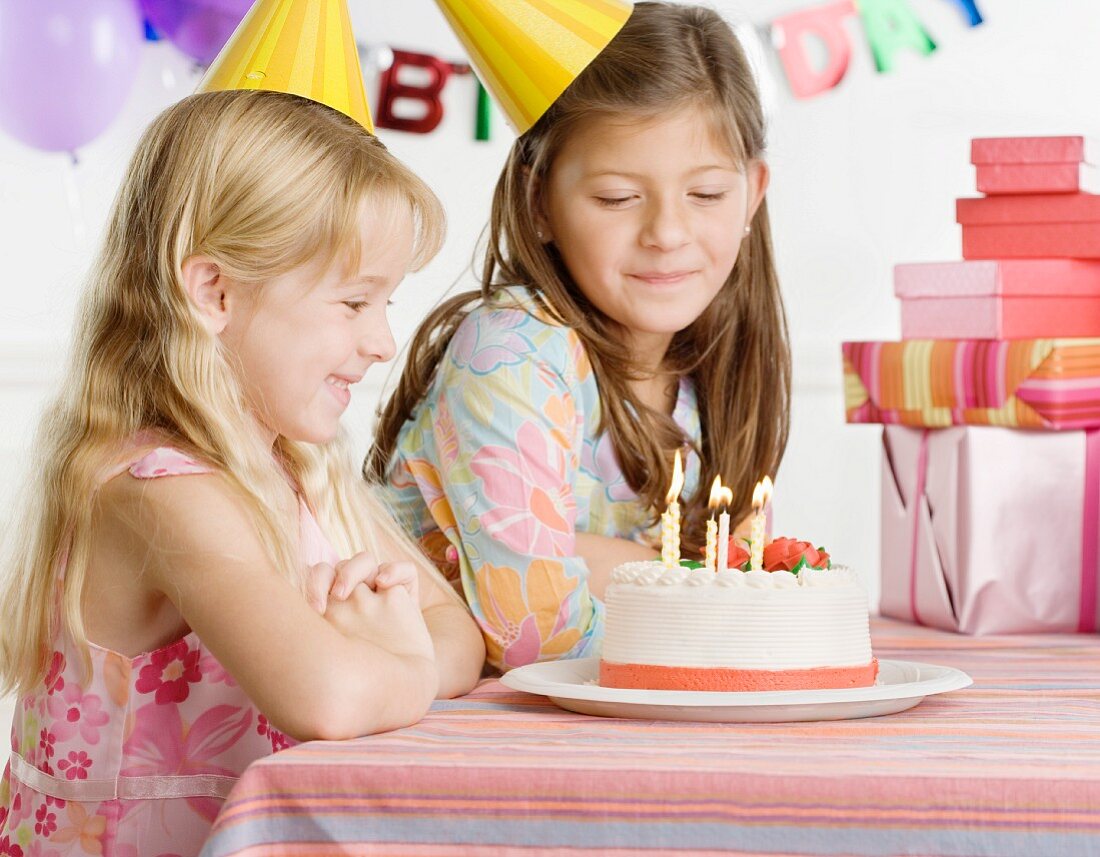 Young sisters with birthday cake at table