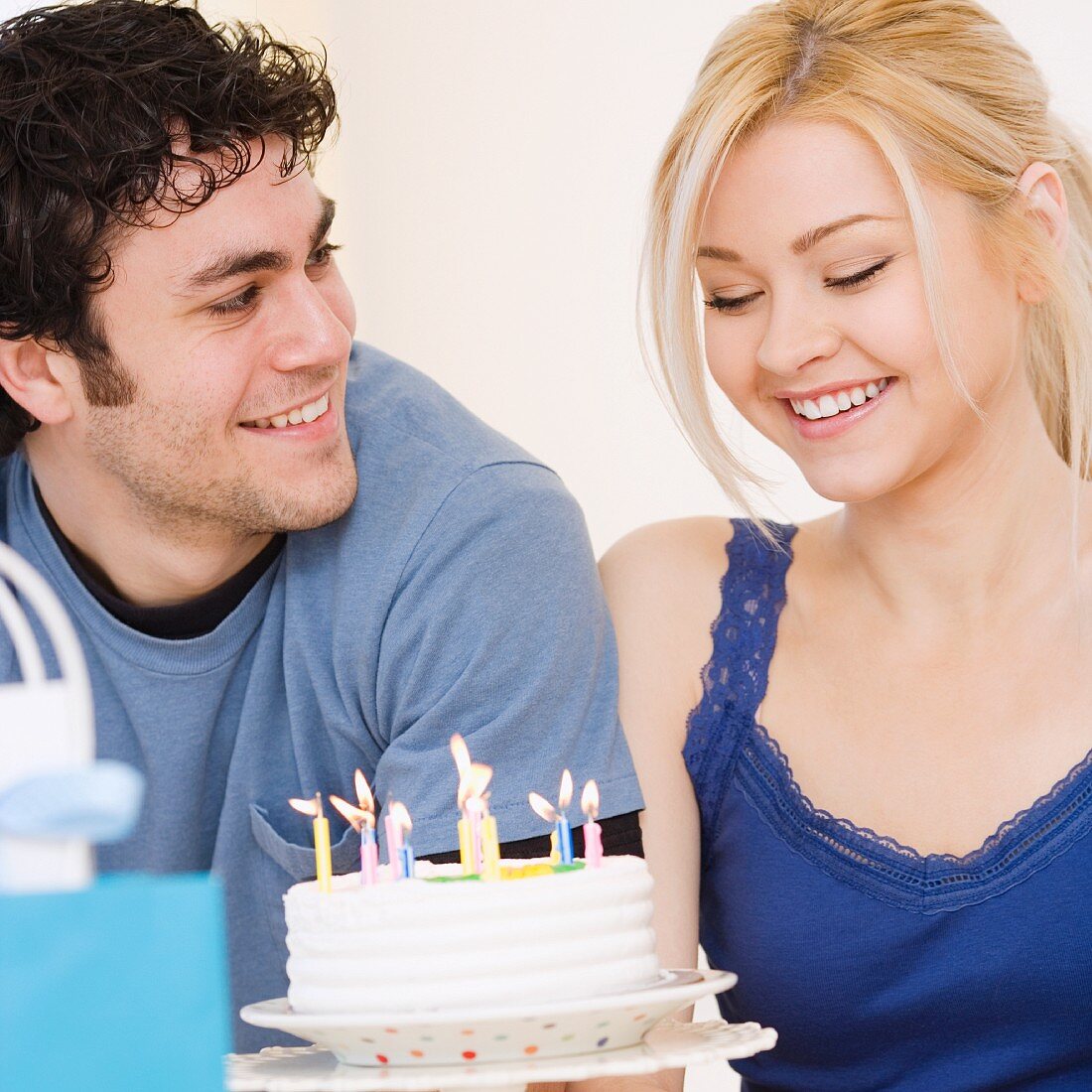 Man watching girlfriend smile at birthday cake