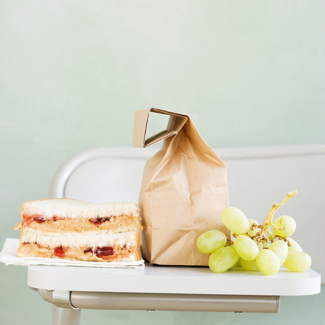 Sandwich and grapes next to paper bag