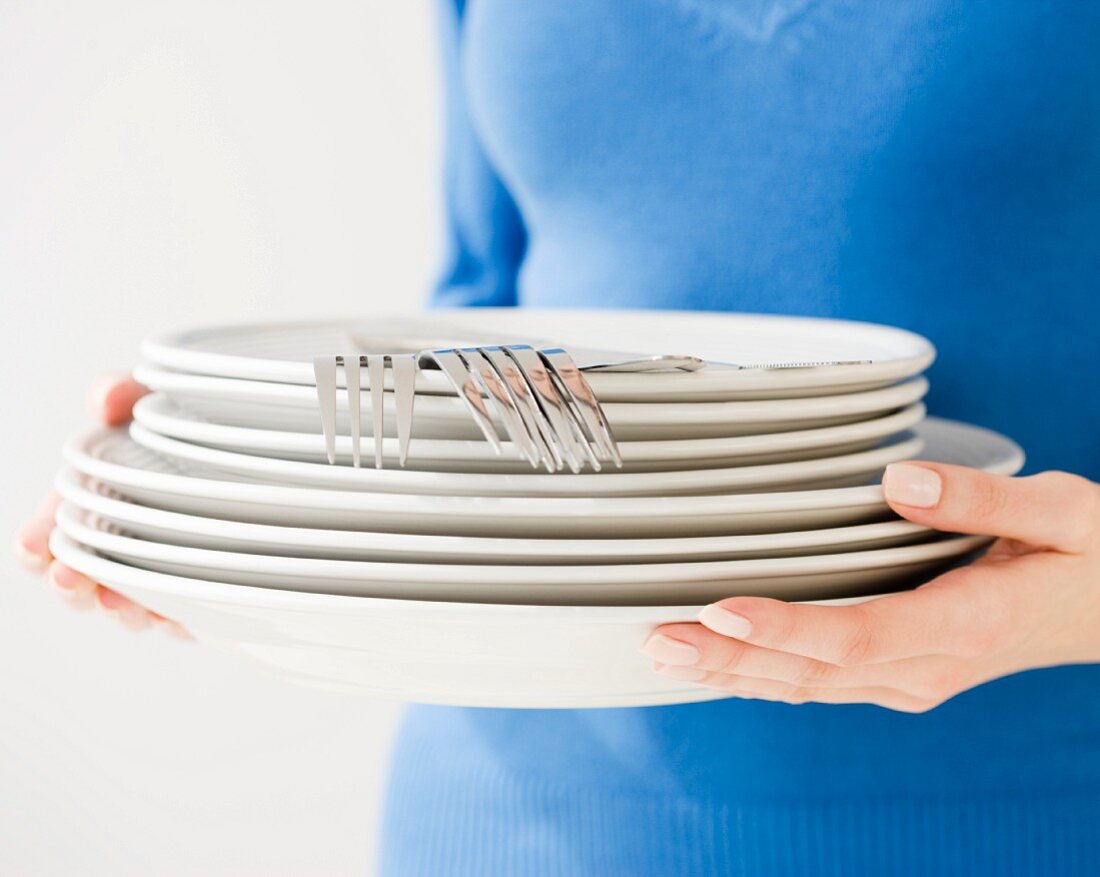 Woman holding stack of dishes