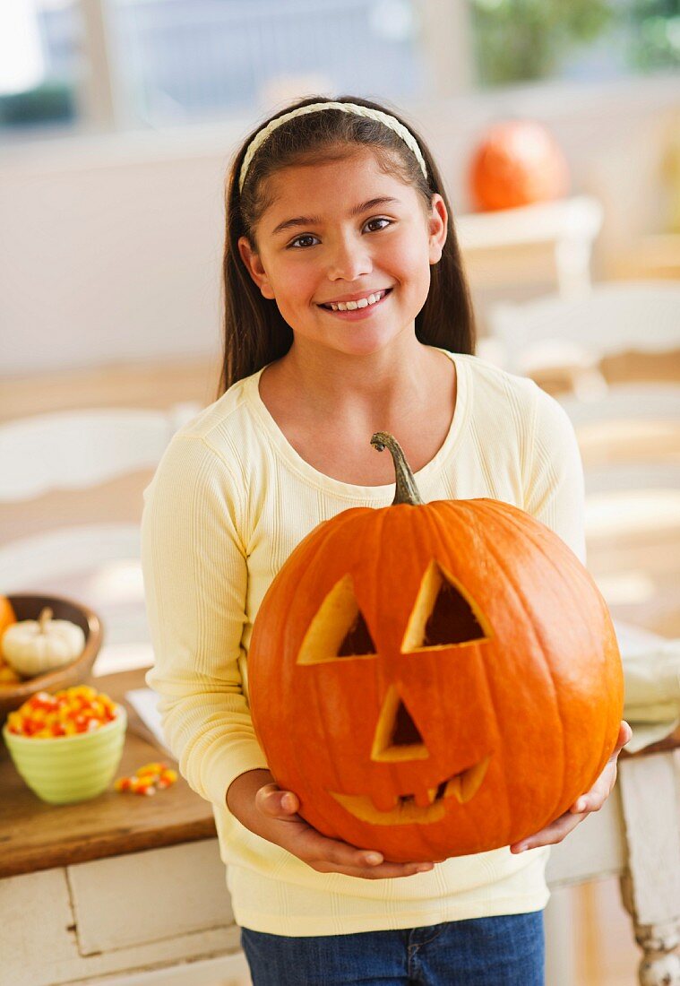 Portrait of girl (10-11) holding Jack o lantern