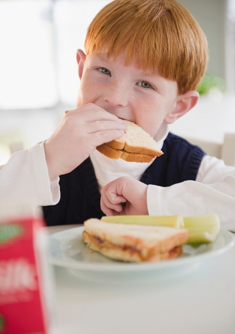 Rothaariger Junge beisst in ein Sandwich