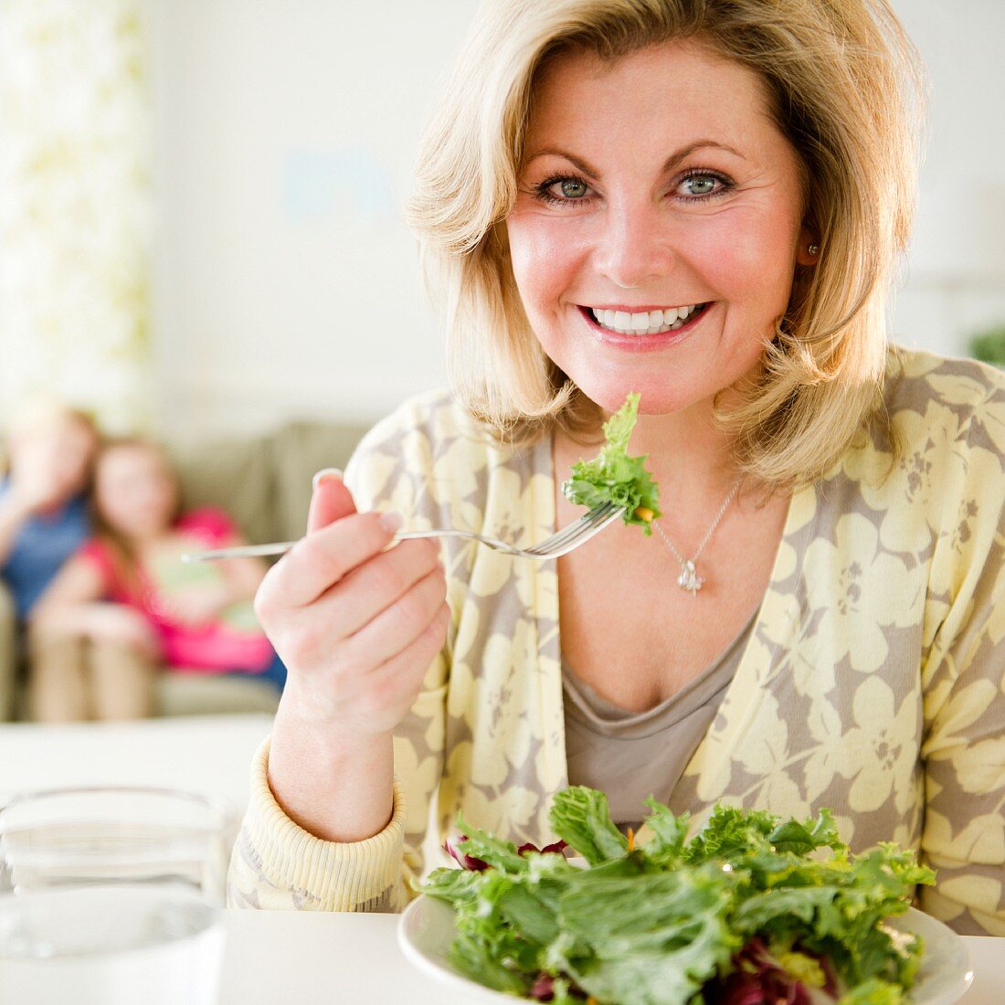A blonde woman eating salad