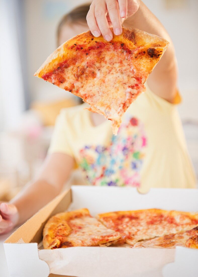 Kind nimmt Pizzastück aus Pizzakaton