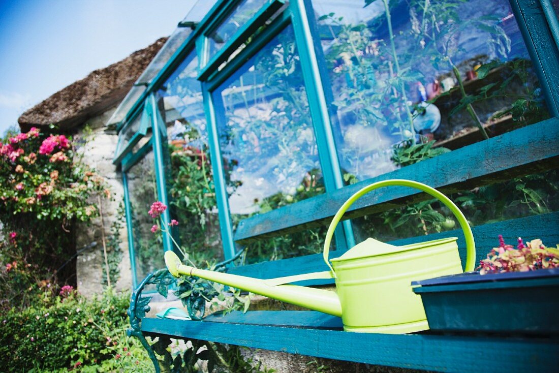 Ireland, County Westmeath, Watering can in front of greenhouse