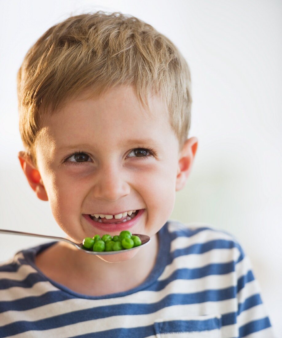 Young boy eating peas